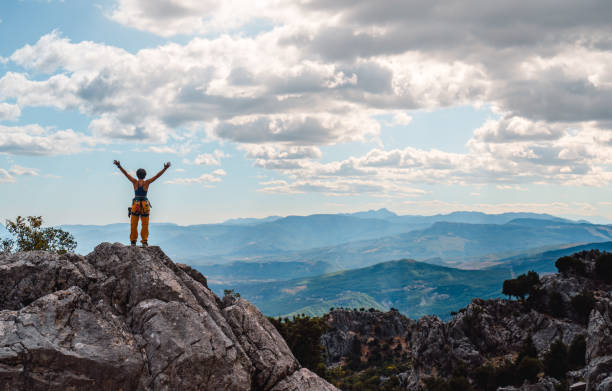 istock Female leader mountain climber is celebrating her success and open her amrs while watching the beautiful scenery of forest  and mountain range on the summit of a mountaing 1434348491