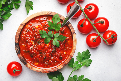 Traditional spicy arrabiata sauce with hot red peppers, garlic and herbs on white kitchen table background, top view. Italian cuisine