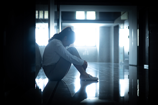 Sadness businesswomen sitting a dark corridor