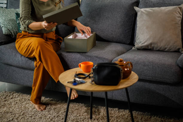 istock Woman sitting on the sofa and opening a package she received in mail 1434351517