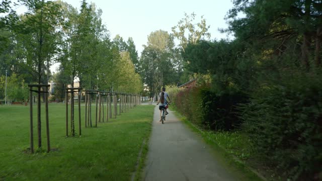 A couple on a tandem bike rides through the park between the trees