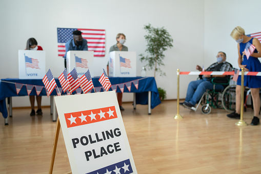 A line of people waiting to vote while voters are standing in the polling booths casting their vote