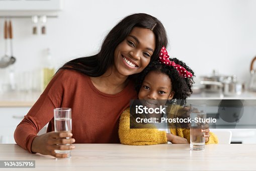 istock Happy African American Family Mother And Daughter Holding Glasses With Water 1434357916