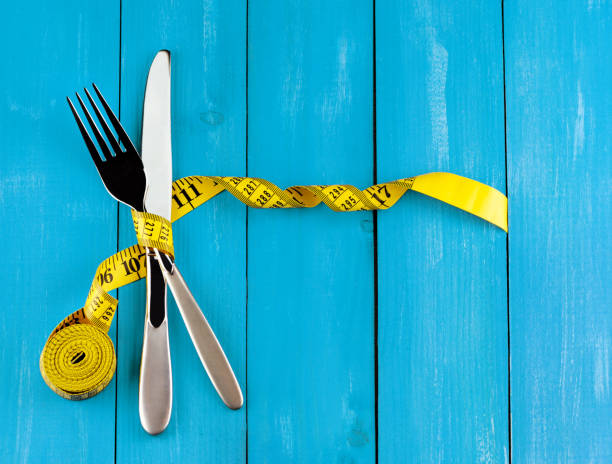 istock Silver fork and knife with yellow measuring tape 1434359848
