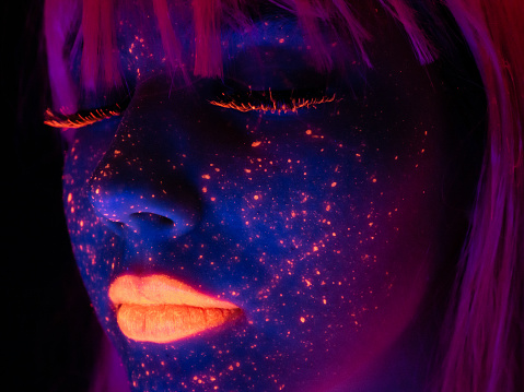 Portrait of a young woman with painted fluorescent make up, eyes closed