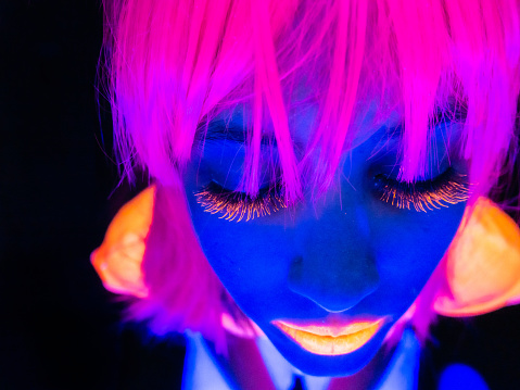 Young woman with eyes closed under UV lights