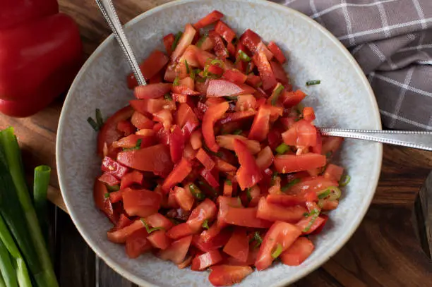 Homemade healthy vegetable salad with chopped tomatoes and bell peppers. Marinated with olive oil and chives.