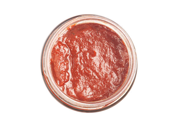 istock Tomato paste in a glass bowl top view isolated on white. 1434368169