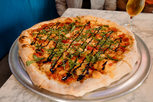 Close-up of a pizza being served in a restaurant. It has tomato cheese and a balsamic glaze. The restaurant is in Newcastle Upon Tyne, North East England.