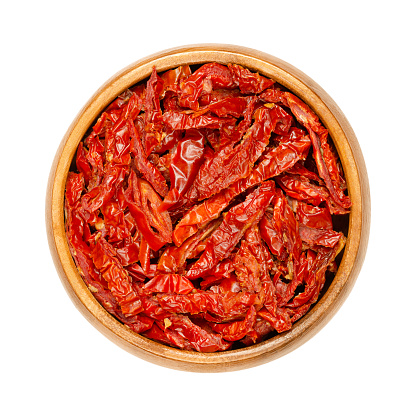 Sun dried tomatoes, in a wooden bowl, isolated from above. Red ripe plum tomatoes, cut into Julienne strips, salted and then dried in the sun of Sicily. High in lycopene, antioxidants and vitamin C.