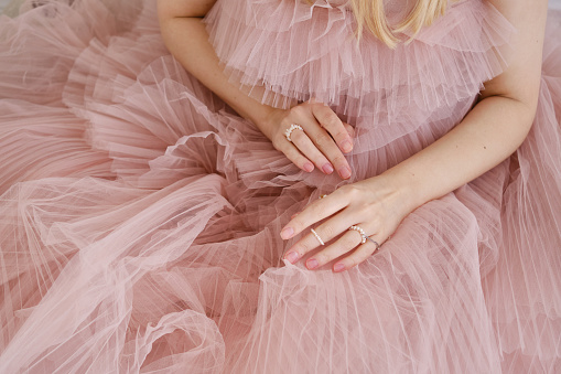 Hermosas manos femeninas sobre un fondo rosa de un vestido hinchado. Estética del minimalismo. El concepto de spa, salones de bodas, tratamientos de manos photo