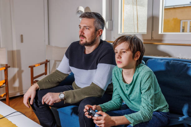 istock Boy holding game console and concentrating on the game, his father watching 1434375972