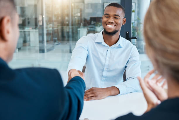 estrechando manos, entrevistadores y empresarios dan un apretón de manos después de contratar a un nuevo empleado de la empresa. incorporación, agradecimiento y la gerencia dan la bienvenida a un joven trabajador africano a una promoción laboral en la  - entrevista fotografías e imágenes de stock