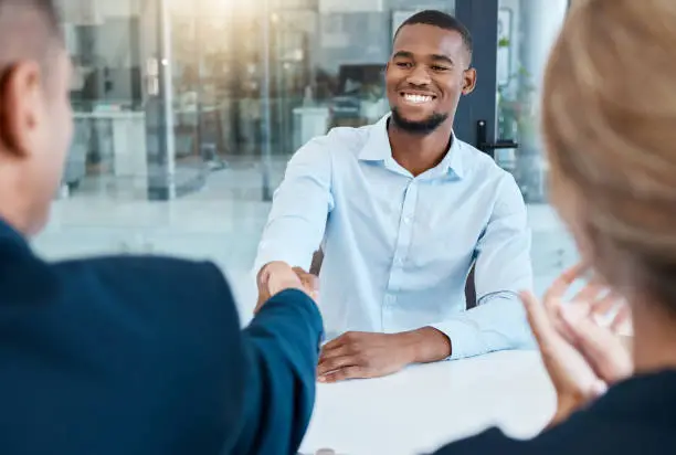 Photo of Shaking hands, interview and business people give a handshake after hiring a new company employee. Onboarding, thank you and management welcome young African worker a job promotion in office meeting