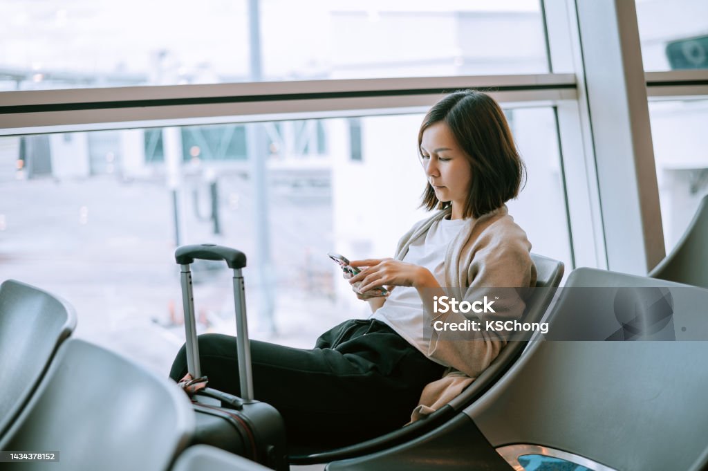 Bored young woman is waiting her flight in airport sitting in hall. Adult, Adults Only, Air Vehicle, Airplane, Airport Airport Stock Photo