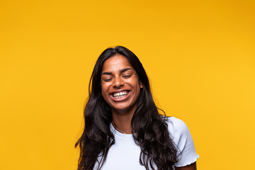 Indian happy young woman laughing isolated on yellow background. Studio shot. Happiness concept.