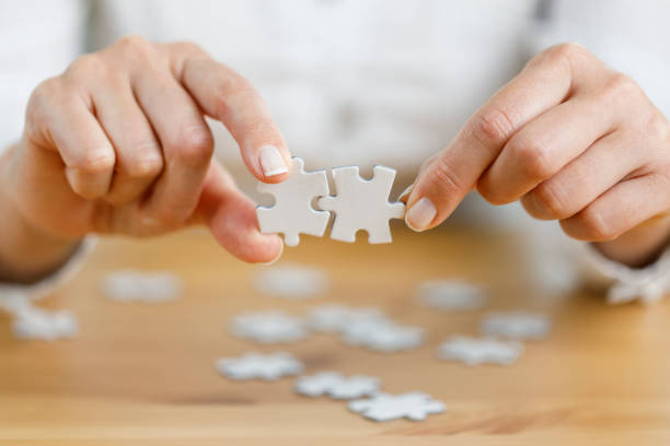istock Woman's hand showing a jigsaw puzzle piece on wooden table 1434380535