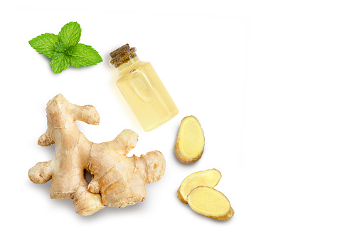 Ginger essential oil and fresh ginger root with slices and mint leaf isolated on white background. Top view. Flat lay. Copy space.