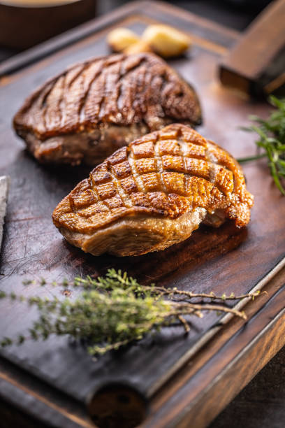 istock Crispy baked duck breast on a cutting board with rosemary and thyme herbs. 1434385764