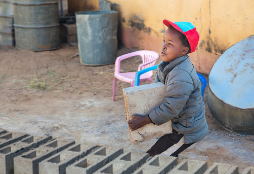 African child working in the village carrying bricks