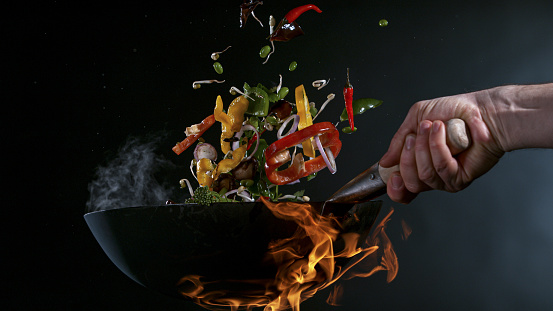 Freeze Motion of Wok Pan with Flying Ingredients in the Air and Fire Flames.