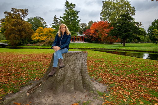 Copenhagen, Denmark A Danish woman sitting on a stump in the Frederiksberg Gardens.