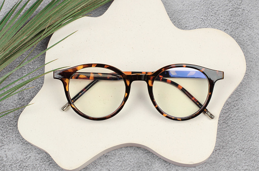 Stylish eyeglasses in leopard color on a beige podium, close-up