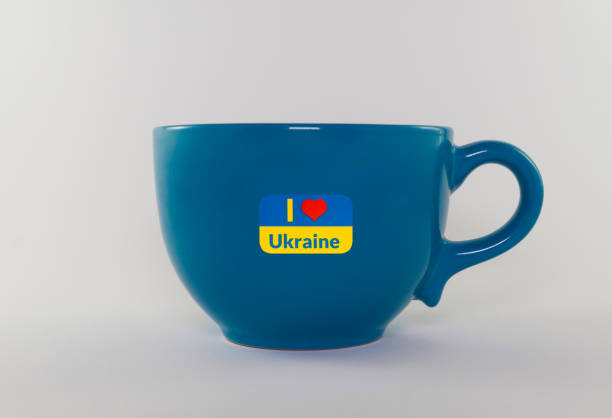 Empty decorative blue cup with one handle on a white background. State symbols of Ukraine are applied on the cup. Close-up. State flag of Ukraine. Stand with Ukraine