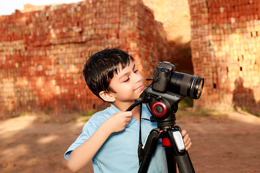 Elementary child of Indian ethnicity using digital camera portrait outdoor.