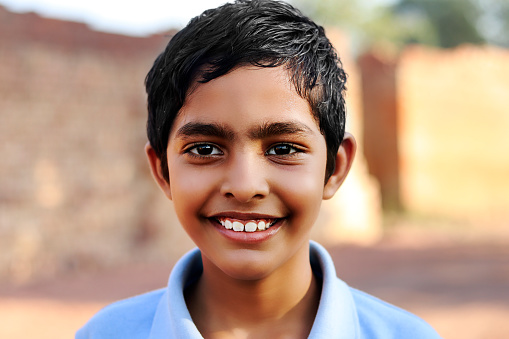 Elementary age cute cheerful child of Indian ethnicity portrait with toothy smile close up.