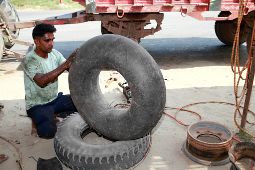Local mechanic of Indian ethnicity working on Tyre puncture shop.