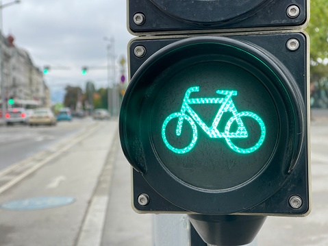 Cropped close up of cycling traffic road lights glowing green, city road on background