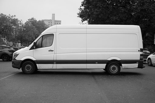 white van parked in open space parking lot. Black and white image