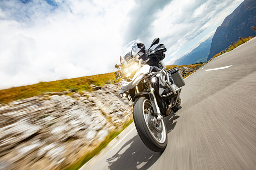 Motorbiker riding in Austrian Alps, dramatic sky. Travel and freedom, outdoor activities