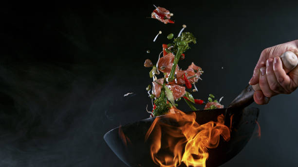 Freeze Motion of Wok Pan and Flying Ingredients in the Air. stock photo