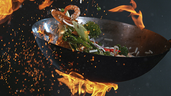 Freeze Motion of Wok Pan with Flying Ingredients in the Air and Fire Flames.