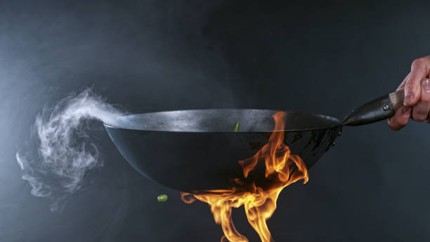 Freeze Motion of Wok Pan and Flying Ingredients in the Air. stock photo