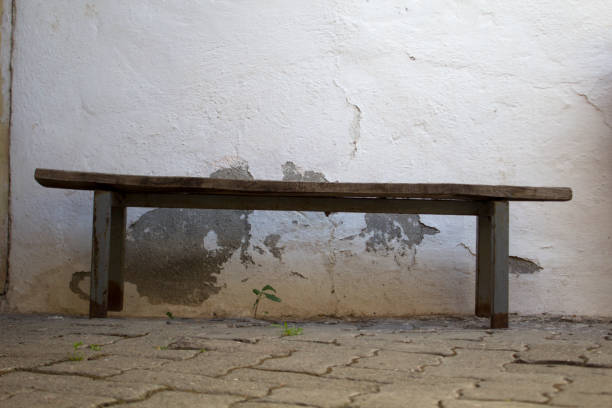 istock Empty old wooden bench in front of damaged white wall 1434408874