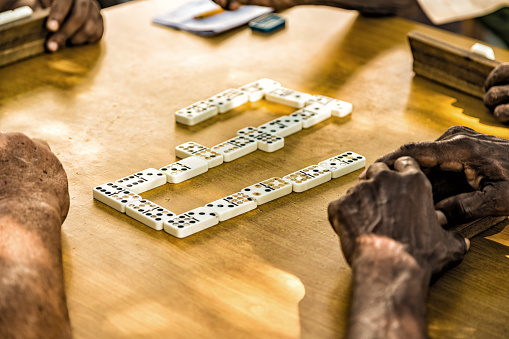 Hands of group of local people playing dominoes on public square in Santiago de Cuba, Cuba.
