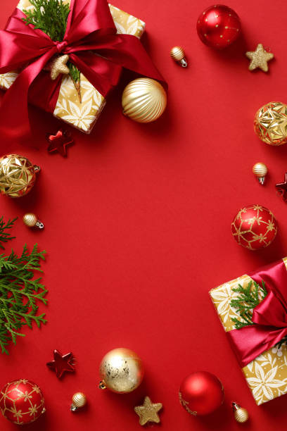 istock Christmas vertical banner. Frame made of gift boxes with red ribbon bow, baubles, Xmas decorations, fir branches on red background. Flat lay, top view, copy space. 1434418018
