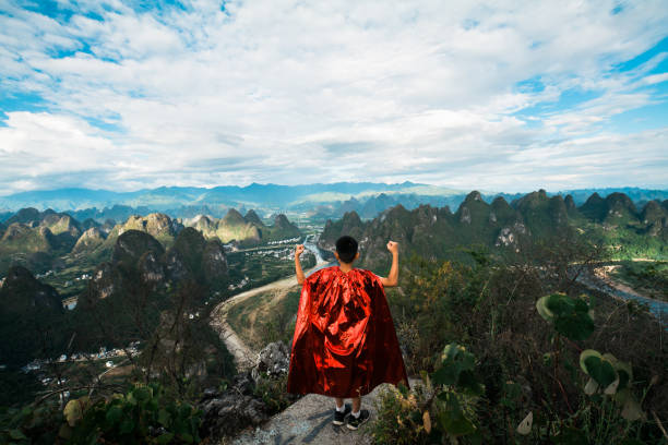 Young superhero showing muscles at mountain peak