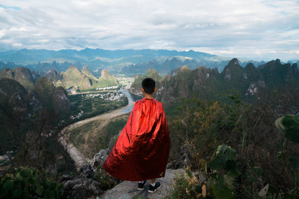 Young superhero looking and contemplating at mountain peak