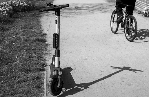 Full length view. Back view of a young girl walks single on bicycle on the road in sunny day time. Black and white view.