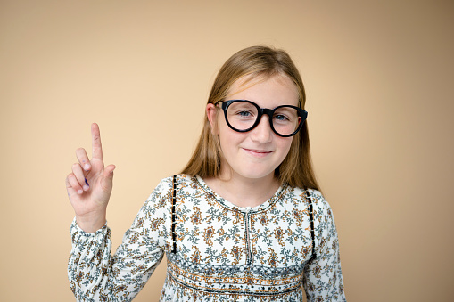 cool schoolgirl with black glasses in front of brown background