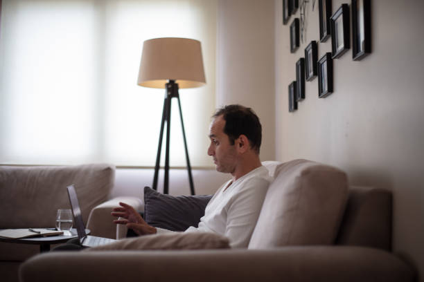 istock Middle-aged man working at home. He is sitting on the sofa. 1434429450