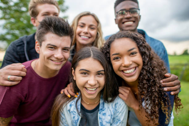 Group Portrait of Teens A small group of diverse teenagers huddle in closely together to pose for a portrait. They are each dressed casually and are smiling. secondary school activities stock pictures, royalty-free photos & images