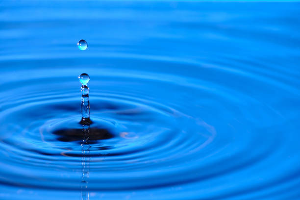 istock Splash drop of water with diverging water circles, on blue background. 1434433839