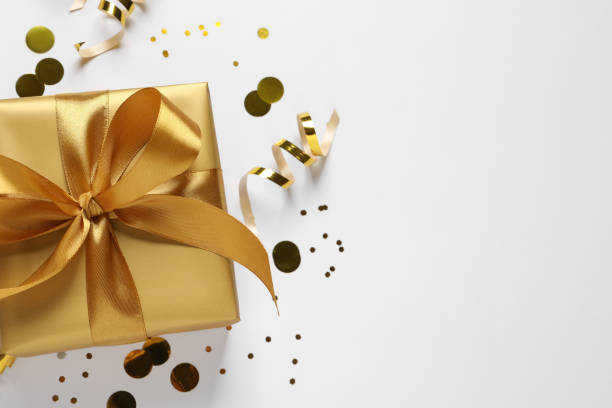 istock Beautiful golden gift box and confetti on white background, flat lay. Space for text 1434434278