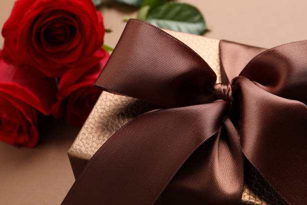 istock Beautiful gift box and flowers on brown background, closeup 1434434837