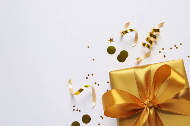 istock Beautiful golden gift box and confetti on white background, flat lay. Space for text 1434435033